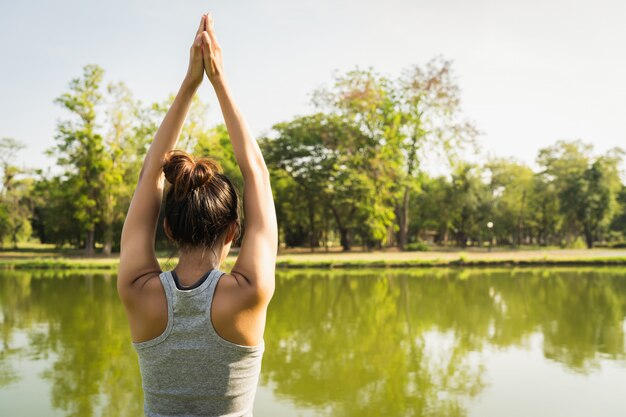 Joven mujer asiática de yoga al aire libre mantiene la calma y medita mientras practica yoga