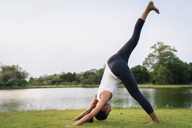 Joven mujer asiática de yoga al aire libre mantiene la calma y medita mientras practica yoga