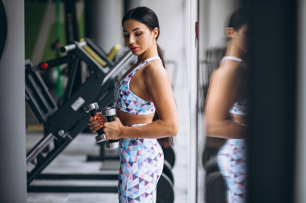 Joven mujer atractiva en el gimnasio con pesas