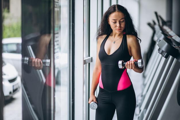 Joven mujer atractiva en el gimnasio con pesas