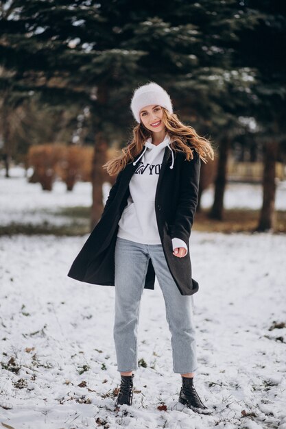 Joven mujer atractiva en un parque de invierno en un lindo sombrero