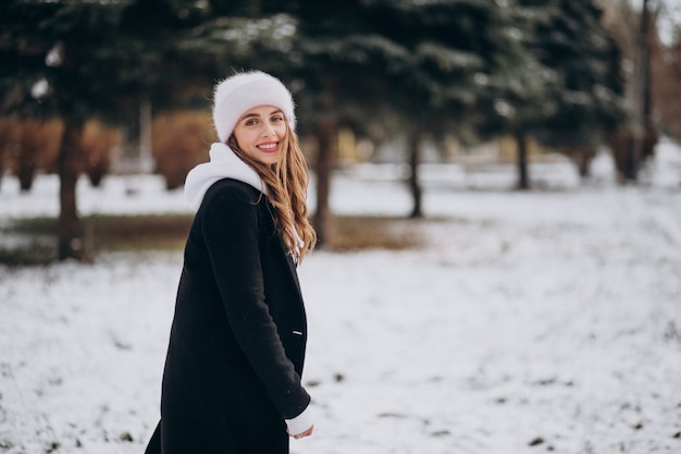 Joven mujer atractiva en un parque de invierno en un lindo sombrero