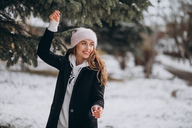 Joven mujer atractiva en un parque de invierno en un lindo sombrero