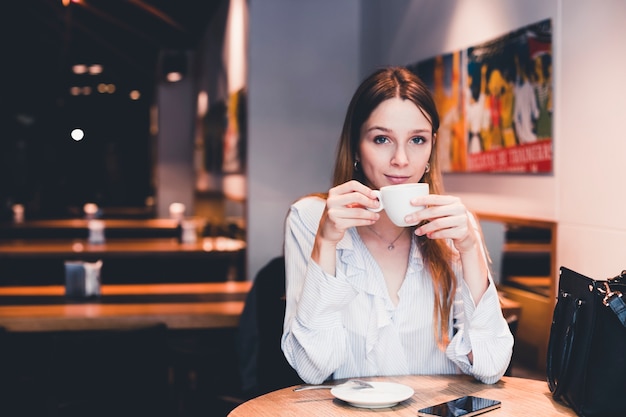 Joven mujer bebiendo en café