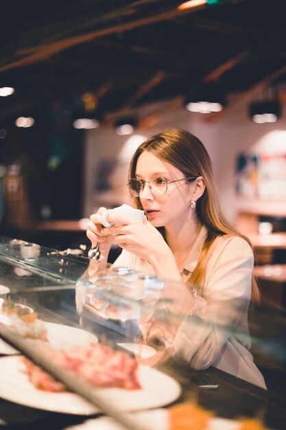 Joven mujer bebiendo en el mostrador de la cafetería