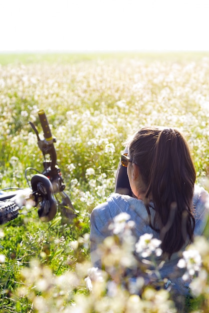 Joven mujer con bicicleta de montaña estirado en el campo