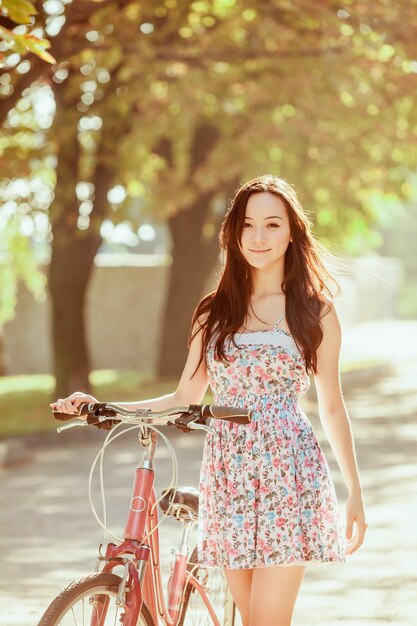 La joven mujer con bicicleta en el parque