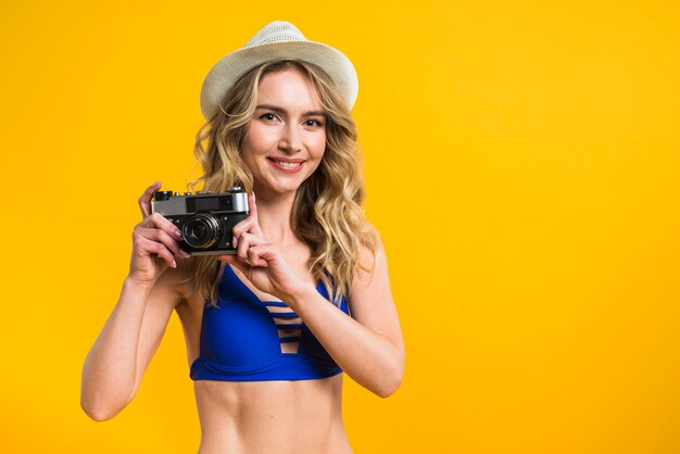 Joven mujer en bikini ofreciendo tomar foto.