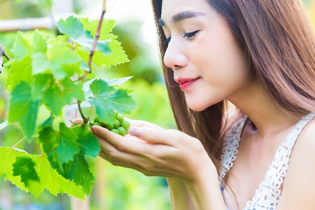 Joven mujer bonita apreciar el árbol de uva felizmente