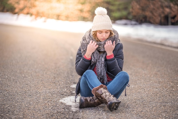 Joven mujer bonita en una carretera con nieve en invierno