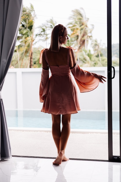 Foto gratuita joven mujer bonita caucásica sola en vestido lindo de verano de vacaciones en villa de lujo