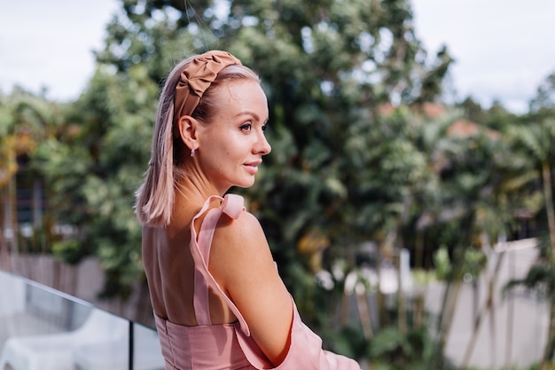 Joven mujer bonita caucásica sola en vestido lindo de verano de vacaciones en villa de lujo