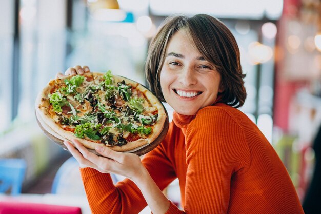 Joven mujer bonita comiendo pizza en el bar de pizza