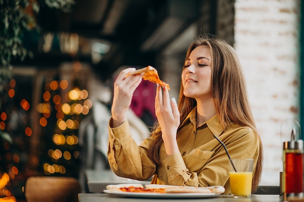 Joven mujer bonita comiendo pizza en un bar