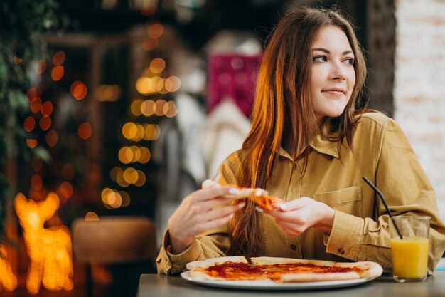 Joven mujer bonita comiendo pizza en un bar