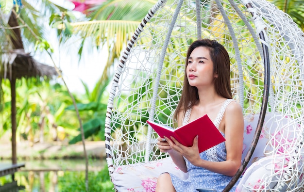 Joven mujer bonita con diario rojo en el parque