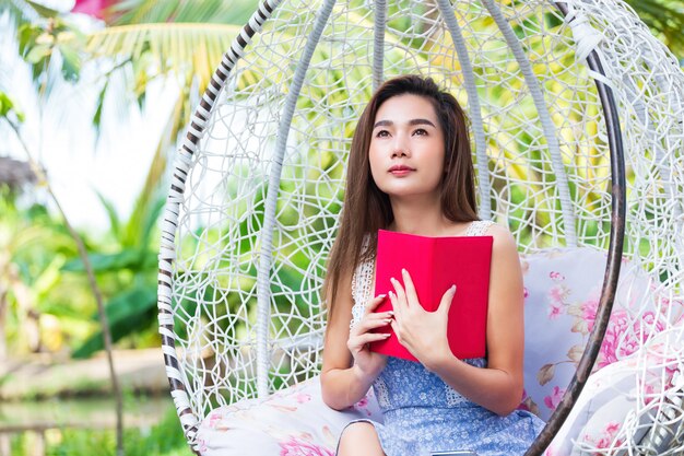 Joven mujer bonita con diario rojo en el parque