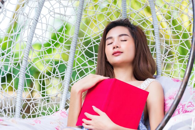 Joven mujer bonita con diario rojo en el parque