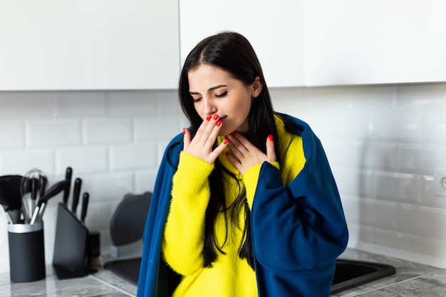 Joven mujer bonita sentirse mal enfermo de pie en la cocina