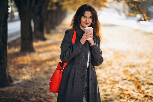 Joven mujer bonita tomando café en el parque