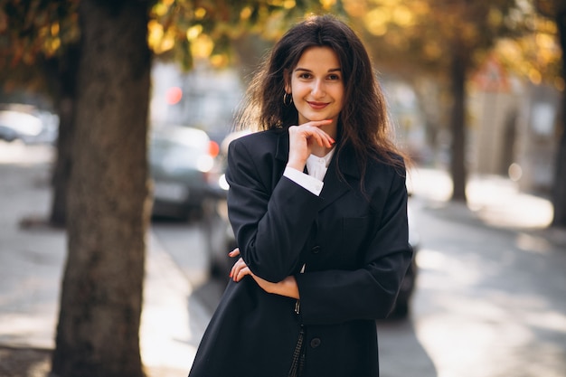 Joven mujer bonita en traje elegante en una calle de otoño