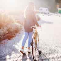 Foto gratuita joven mujer caminando con bicicleta