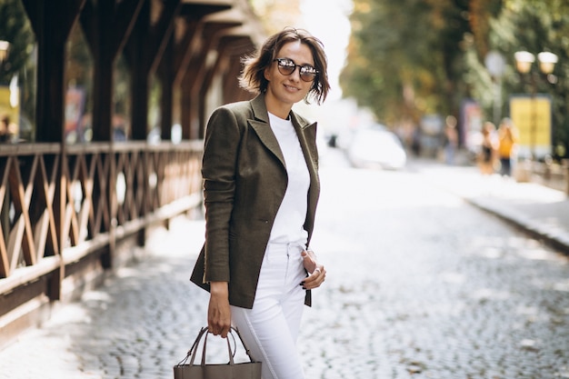 Foto gratuita joven mujer caminando en la ciudad en gafas de sol