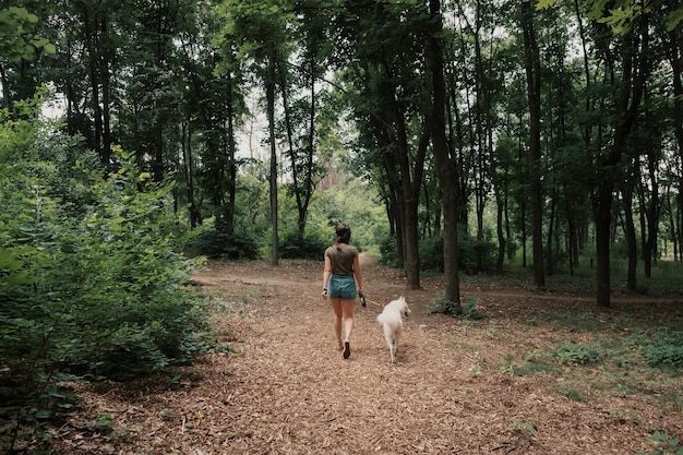 Joven mujer caminando con un husky blanco