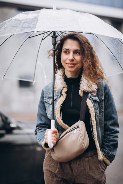 Joven mujer caminando bajo la lluvia con paraguas