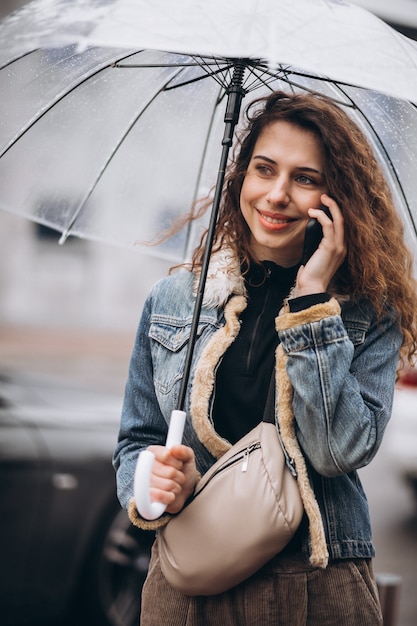 Joven mujer caminando bajo la lluvia con paraguas