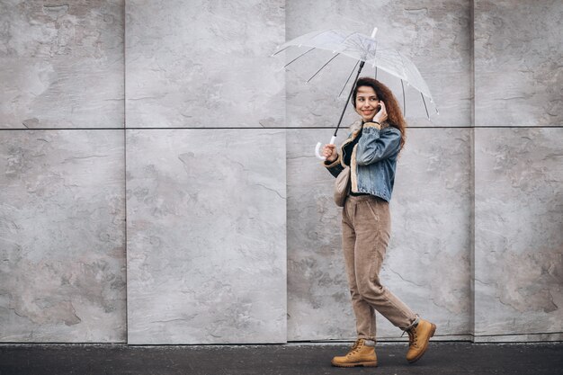 Joven mujer caminando bajo la lluvia con paraguas