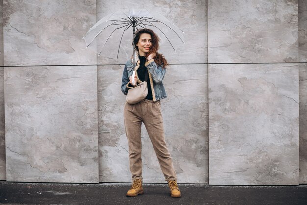 Joven mujer caminando bajo la lluvia con paraguas