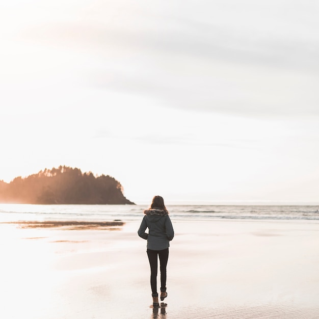 Joven mujer caminando hacia el mar