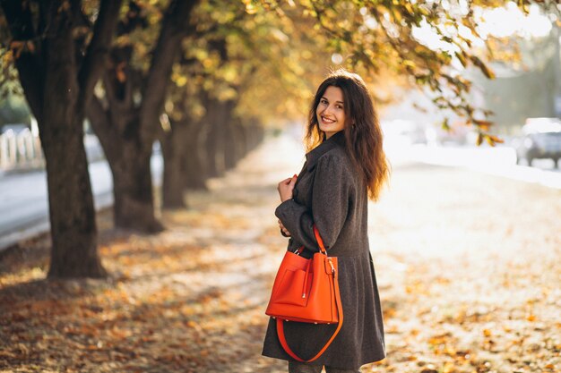 Joven mujer caminando en un parque de otoño