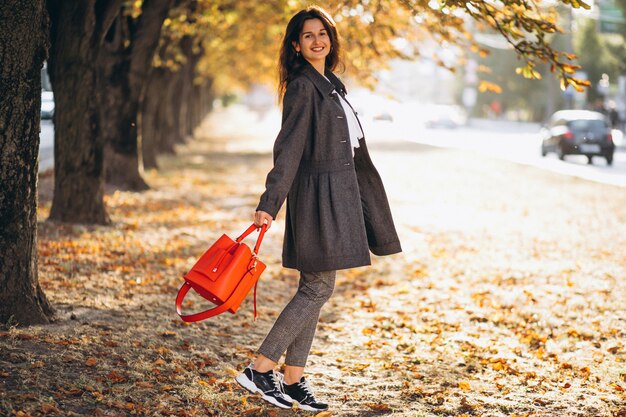 Joven mujer caminando en un parque de otoño