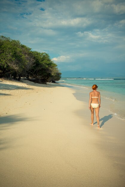 Joven mujer caminando por la playa tropical