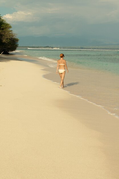 Joven mujer caminando por la playa tropical