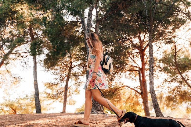 Joven mujer caminando con su perro en el parque