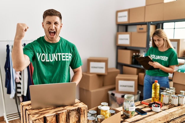 Un joven y una mujer con una camiseta de voluntarios en las donaciones están molestos y frustrados gritando de ira, gritando locos de ira y levantando la mano