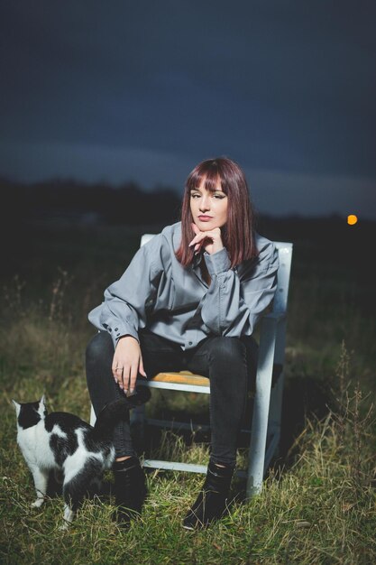 Foto gratuita joven mujer caucásica de bosnia y herzegovina en una camisa gris sentada en una silla con su gato