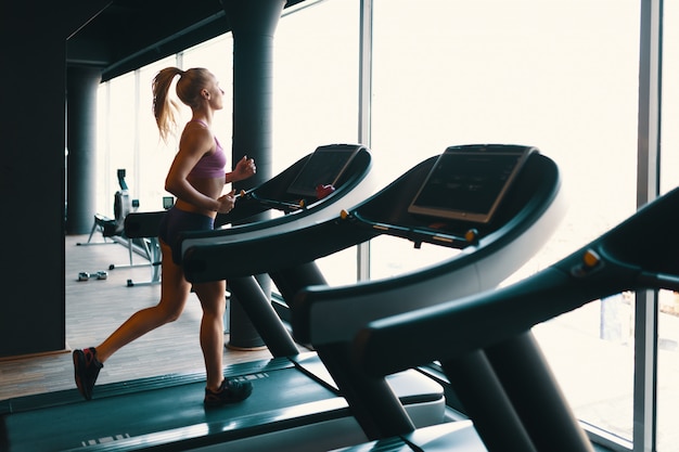 Joven mujer caucásica haciendo ejercicio con pesas mientras entrena brazos en el gimnasio