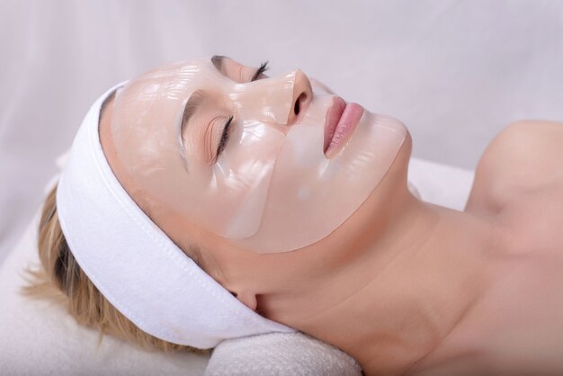 Joven mujer caucásica con máscara de piel en su rostro en el spa