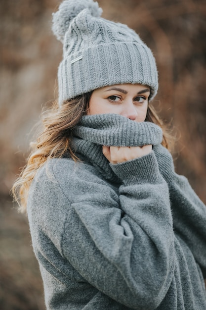 Joven mujer caucásica vistiendo un suéter gris y gorro de invierno