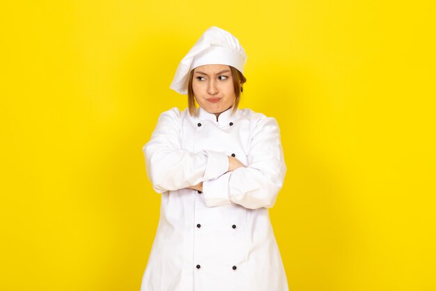 Joven mujer cocinando en traje de cocinero blanco y gorra blanca enojado expresión disgustado