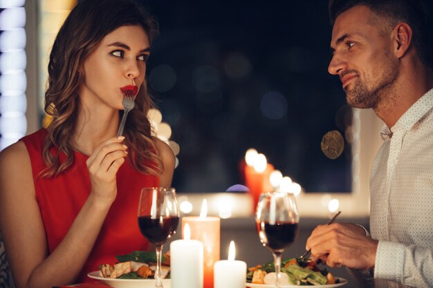 Joven mujer comiendo y coqueteando con su hombre mientras cena romántica