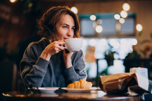 Joven mujer comiendo croissants en un café