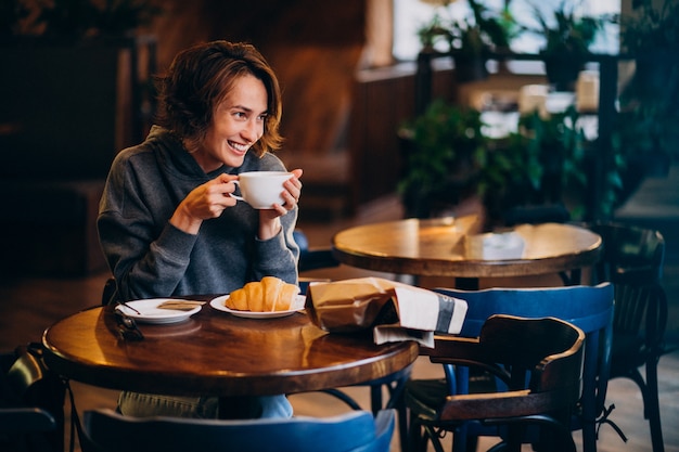 Foto gratuita joven mujer comiendo croissants en un café