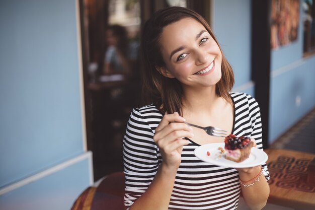 Joven mujer comiendo tarta de fresa