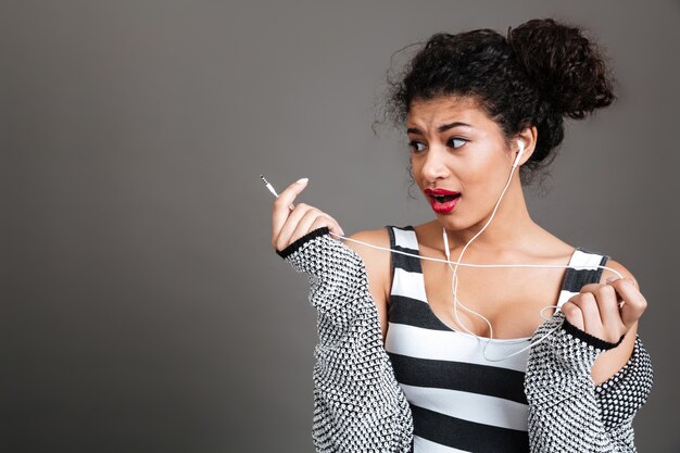 Joven mujer confundida con auriculares rotos