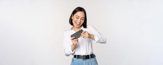 Joven mujer coreana chica asiática jugando videojuegos móviles en el teléfono inteligente mirando el teléfono horizontal sc